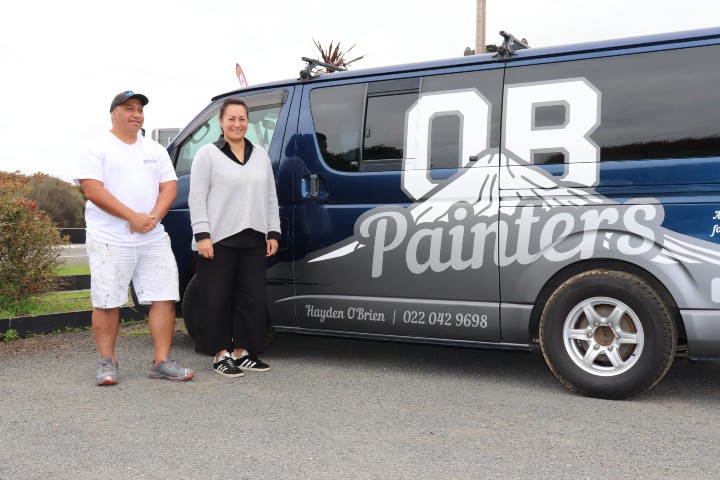 Hayden and Rohario from Waha Digital stand proudly beside a van painted with OB Painters logo with a mountain and Hayden's contact on it.