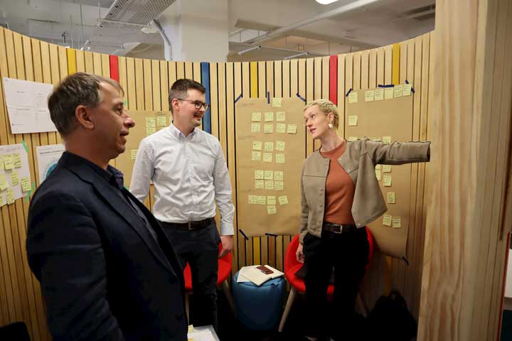 Brent, Matt and Holly from the Digital Consent team standing at a wall of Post-it notes, doing customer-journey mapping.