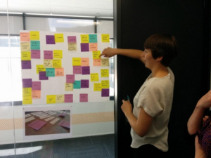 Designer Meg Howie pointing at post-it notes stuck to a wall.