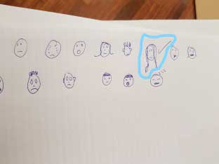 Children's drawings of faces with a smiling face circled.