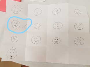 Children's drawings of faces with a winking face circled.