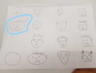 Children's drawings of faces with a smiling face circled.