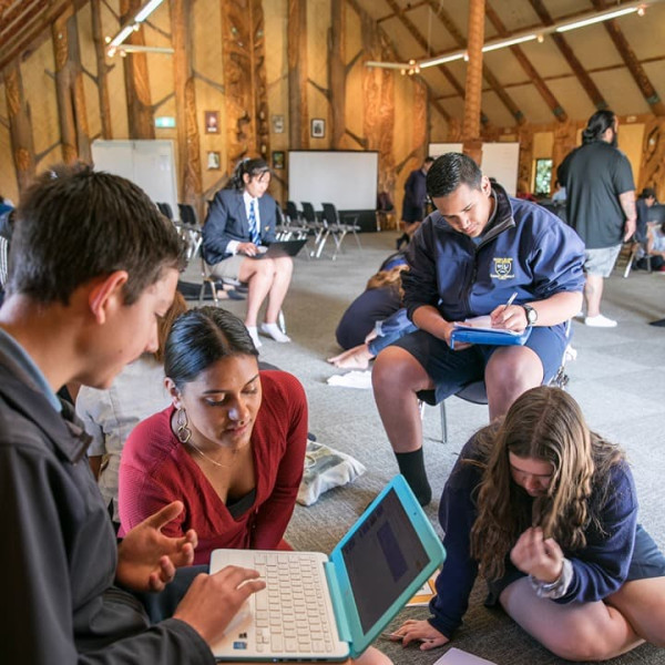 Photograph of students using their digital devices in a marae meeting house.
