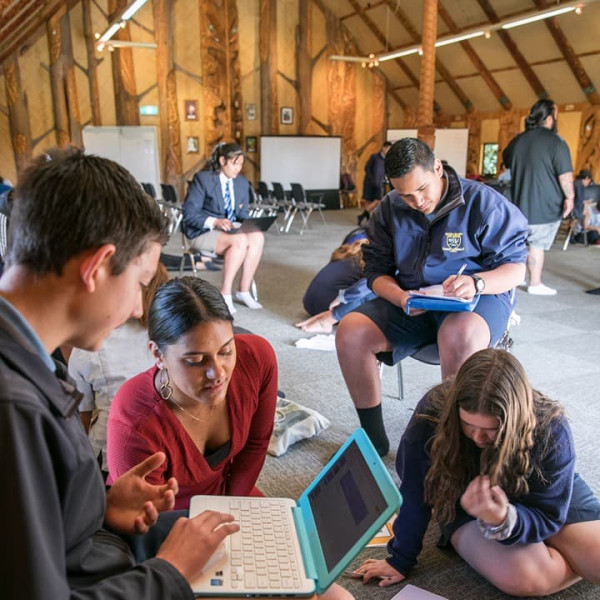 He whakaahua o ngā ākonga e whakamahi i ā rātau pūrere i roto i tētahi tipuna whare.